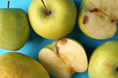 Photo of Damaged green apples on light blue background, closeup