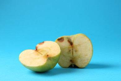 Photo of Halves of damaged apple on light blue background. Space for text