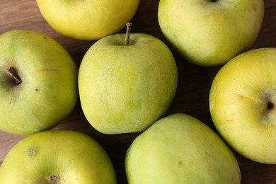 Photo of Many damaged green apples on wooden table, closeup