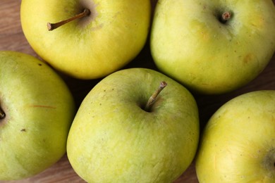 Photo of Many damaged green apples on wooden table, closeup