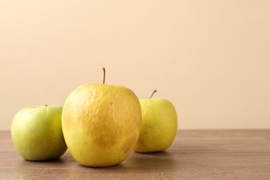 Photo of Many damaged green apples on wooden table. Space for text