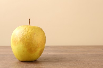 Photo of One rotten green apple on wooden table. Space for text