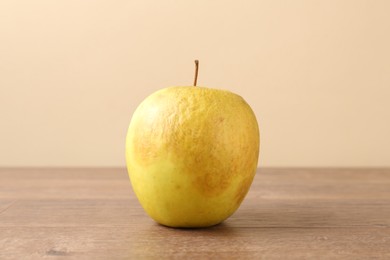 Photo of One rotten green apple on wooden table