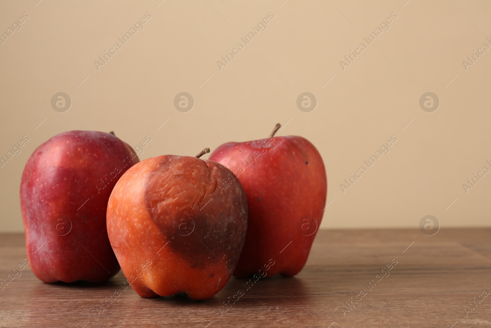 Many rotten red apples on wooden table Photo of Many rotten red apples on wooden table