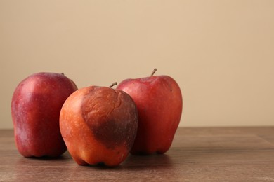 Photo of Many rotten red apples on wooden table
