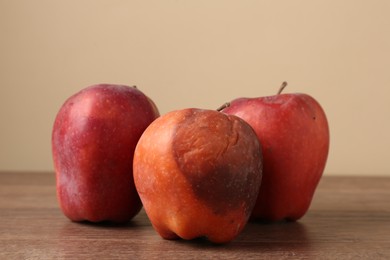 Photo of Many rotten red apples on wooden table