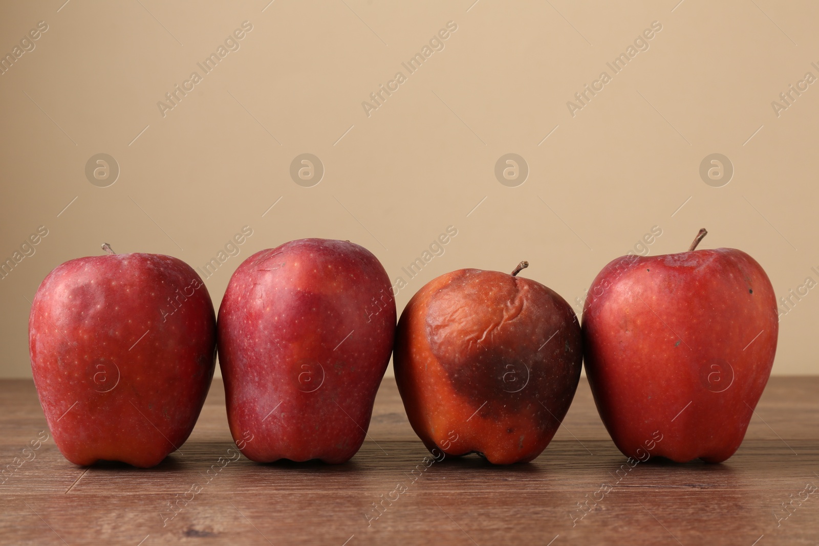 Many rotten red apples on wooden table. Space for text Photo of Many rotten red apples on wooden table. Space for text