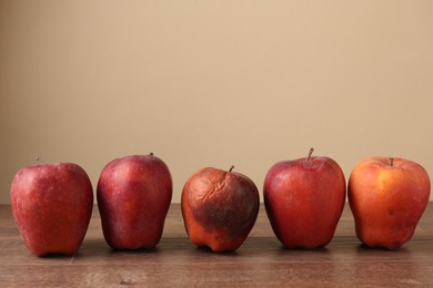 Photo of Many rotten red apples on wooden table. Space for text