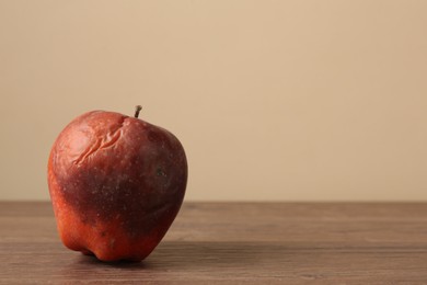 Photo of One rotten red apple on wooden table. Space for text