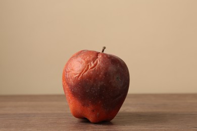 Photo of One rotten red apple on wooden table
