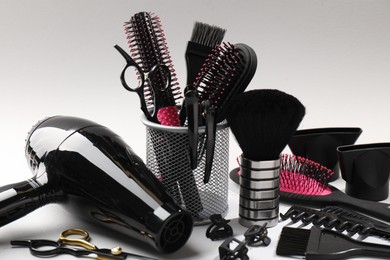 Photo of Different hairdresser's tools on light grey background, closeup