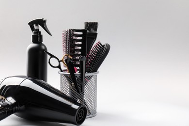 Photo of Different hairdresser's tools on light grey background, closeup. Space for text