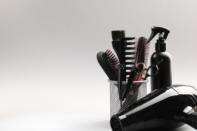 Photo of Different hairdresser's tools on light grey background, closeup. Space for text
