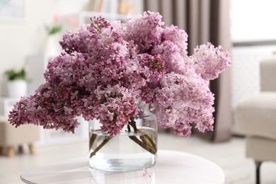 Photo of Beautiful lilac flowers in vase on table indoors
