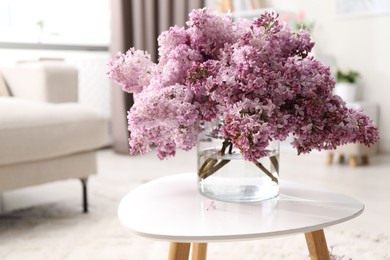 Photo of Beautiful lilac flowers in vase on table indoors, space for text