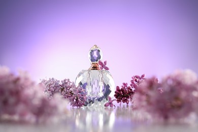 Photo of Beautiful lilac flowers and perfume on mirror surface against violet gradient background