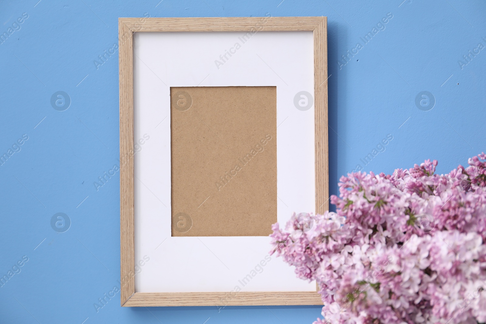 Beautiful lilac flowers and picture frame on light blue background, closeup Photo of Beautiful lilac flowers and picture frame on light blue background, closeup