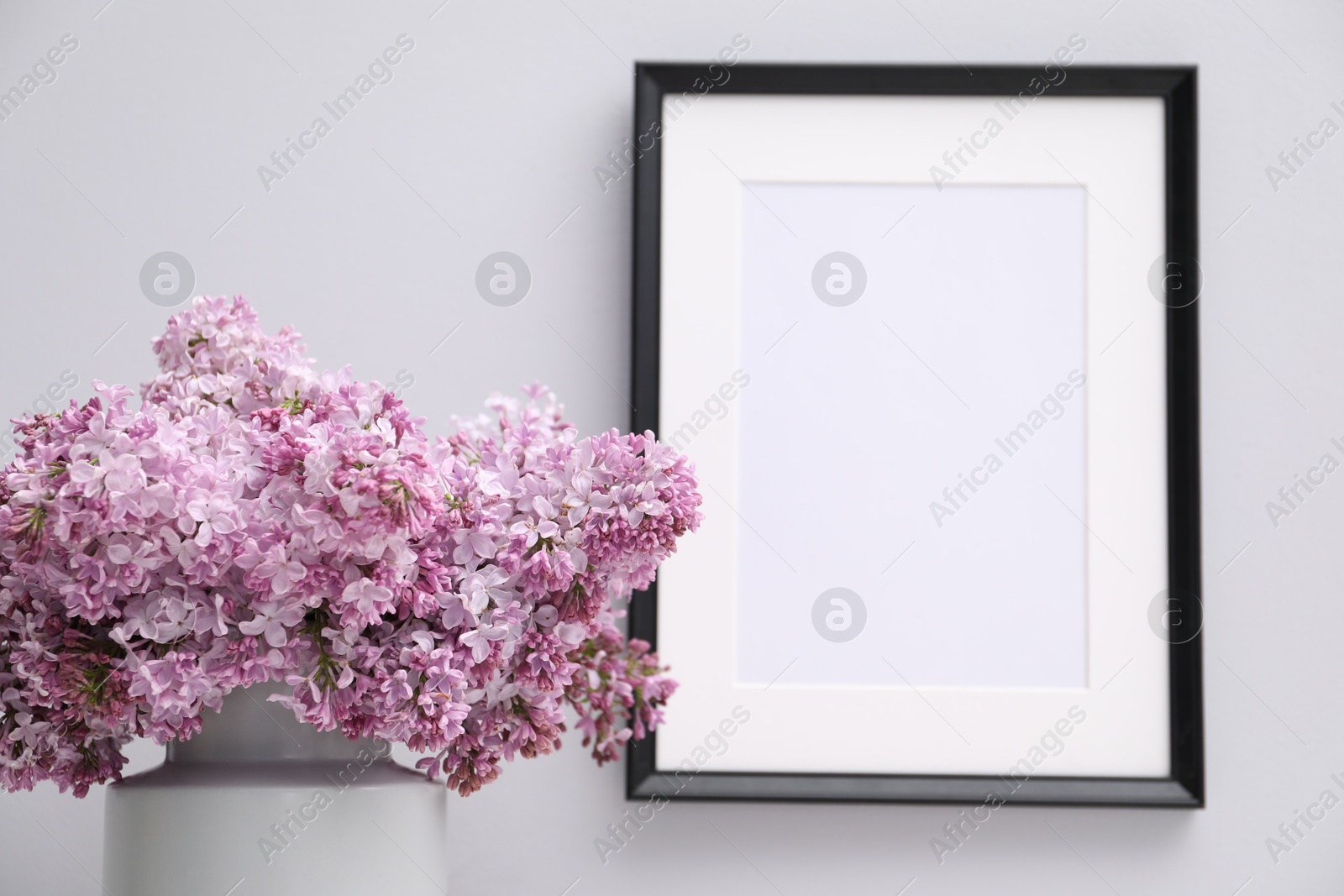 Beautiful lilac flowers in vase and picture frame on white background, closeup Photo of Beautiful lilac flowers in vase and picture frame on white background, closeup