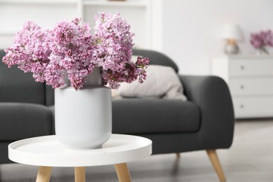Photo of Beautiful lilac flowers in vase on table indoors, space for text