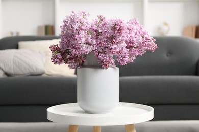 Photo of Beautiful lilac flowers in vase on table indoors