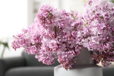 Photo of Beautiful lilac flowers in vase indoors, closeup
