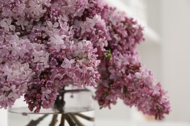 Photo of Beautiful lilac flowers in vase indoors, closeup