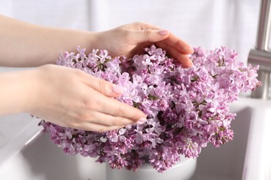 Photo of Woman with beautiful lilac flowers indoors, closeup