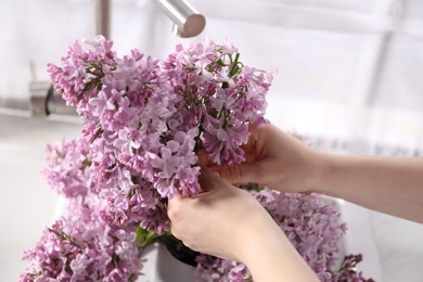 Photo of Woman with beautiful lilac flowers indoors, closeup