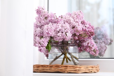 Photo of Beautiful lilac flowers in glass vase on window sill indoors