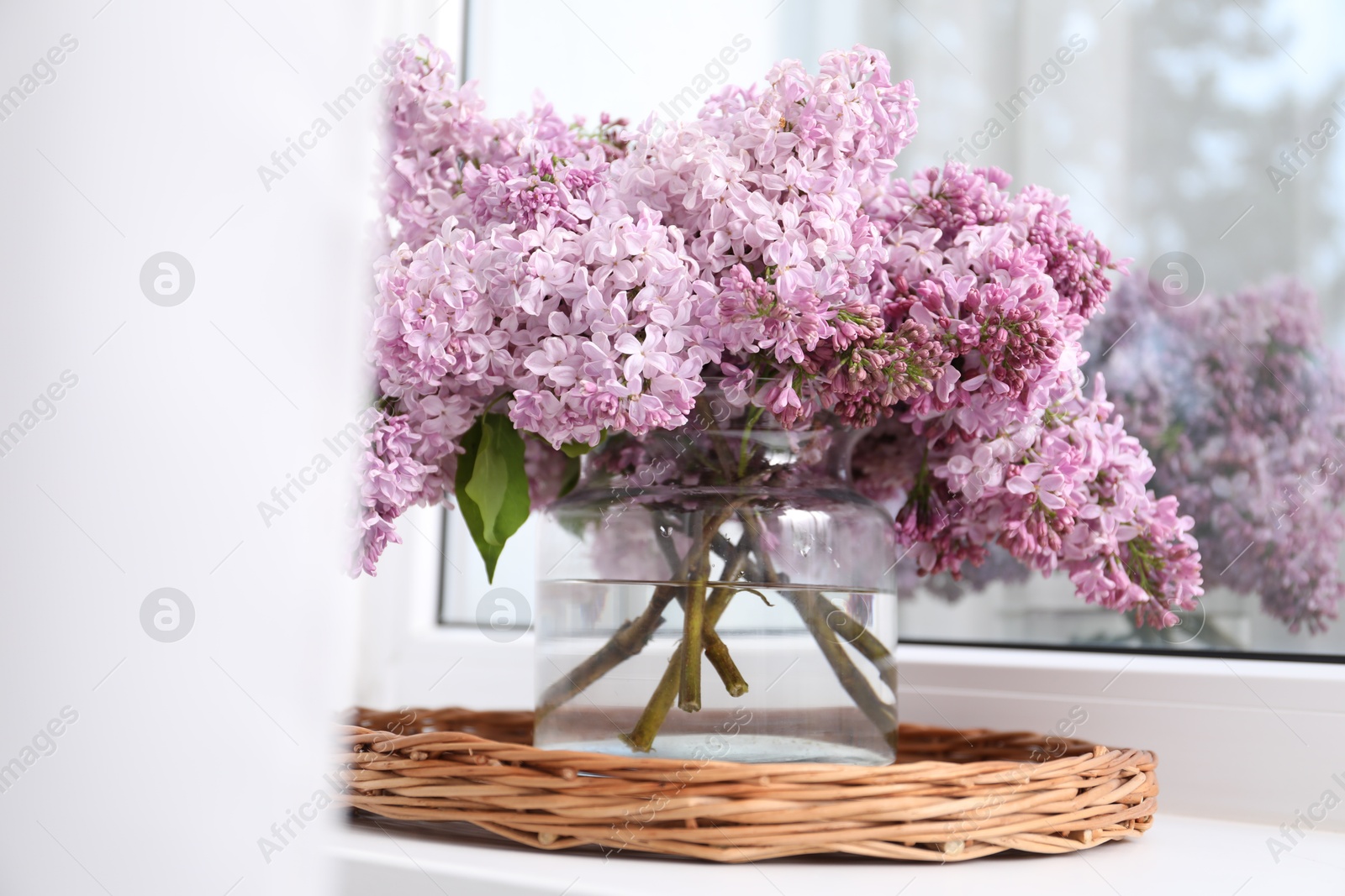 Beautiful lilac flowers in glass vase on window sill indoors Photo of Beautiful lilac flowers in glass vase on window sill indoors