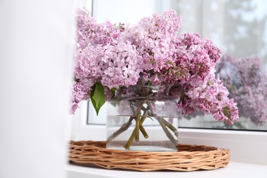 Photo of Beautiful lilac flowers in glass vase on window sill indoors