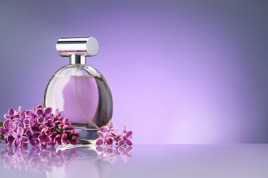 Photo of Beautiful lilac flowers and perfume on mirror surface against violet gradient background, space for text