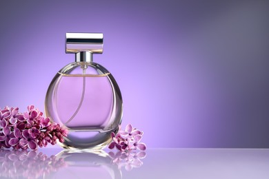 Photo of Beautiful lilac flowers and perfume on mirror surface against violet gradient background, space for text