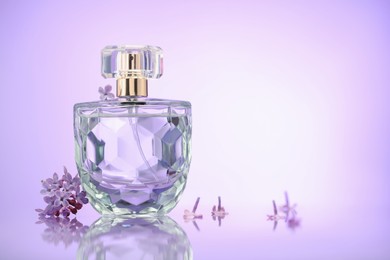 Photo of Beautiful lilac flowers and perfume on mirror surface against violet gradient background, space for text