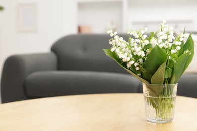 Photo of Bouquet of beautiful lily-of-the-valley on wooden table indoors. Space for text