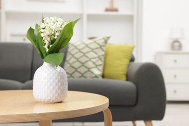 Photo of Bouquet of beautiful lily-of-the-valley in vase on coffee table indoors. Space for text