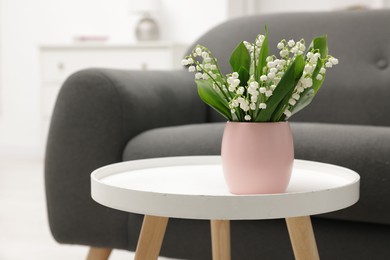 Photo of Bouquet of beautiful lily-of-the-valley on coffee table indoors
