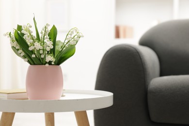 Photo of Bouquet of beautiful lily-of-the-valley on coffee table indoors. Space for text