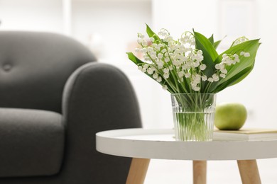 Photo of Bouquet of beautiful lily-of-the-valley on coffee table indoors. Space for text