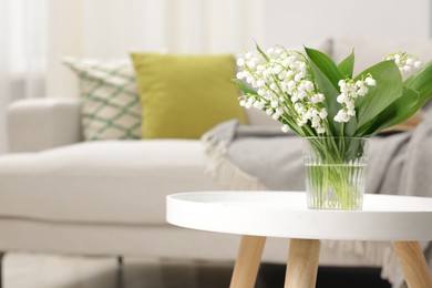Photo of Bouquet of beautiful lily-of-the-valley on coffee table indoors. Space for text