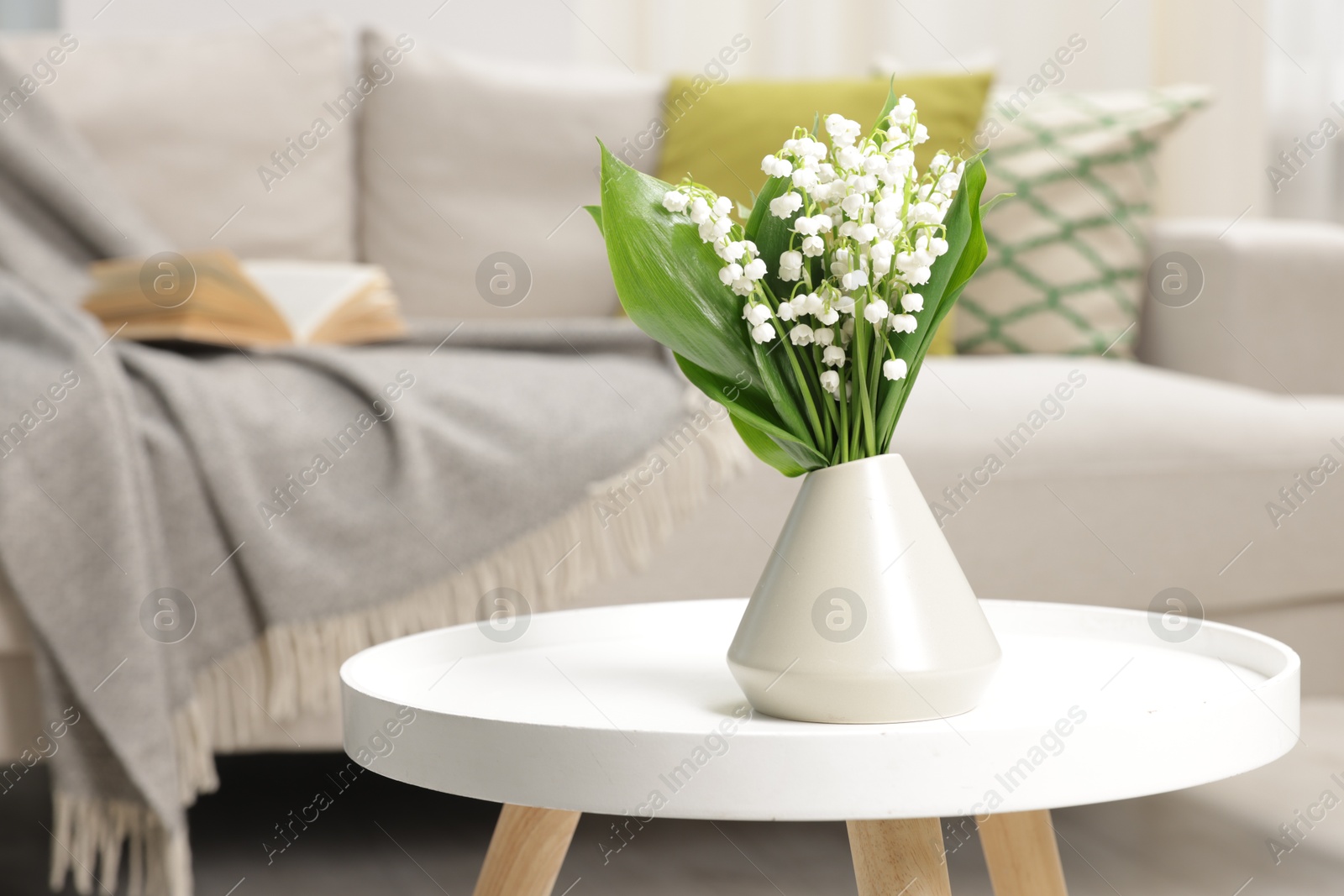 Bouquet of beautiful lily-of-the-valley in vase on coffee table indoors Photo of Bouquet of beautiful lily-of-the-valley in vase on coffee table indoors