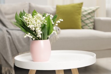 Photo of Bouquet of beautiful lily-of-the-valley on coffee table indoors
