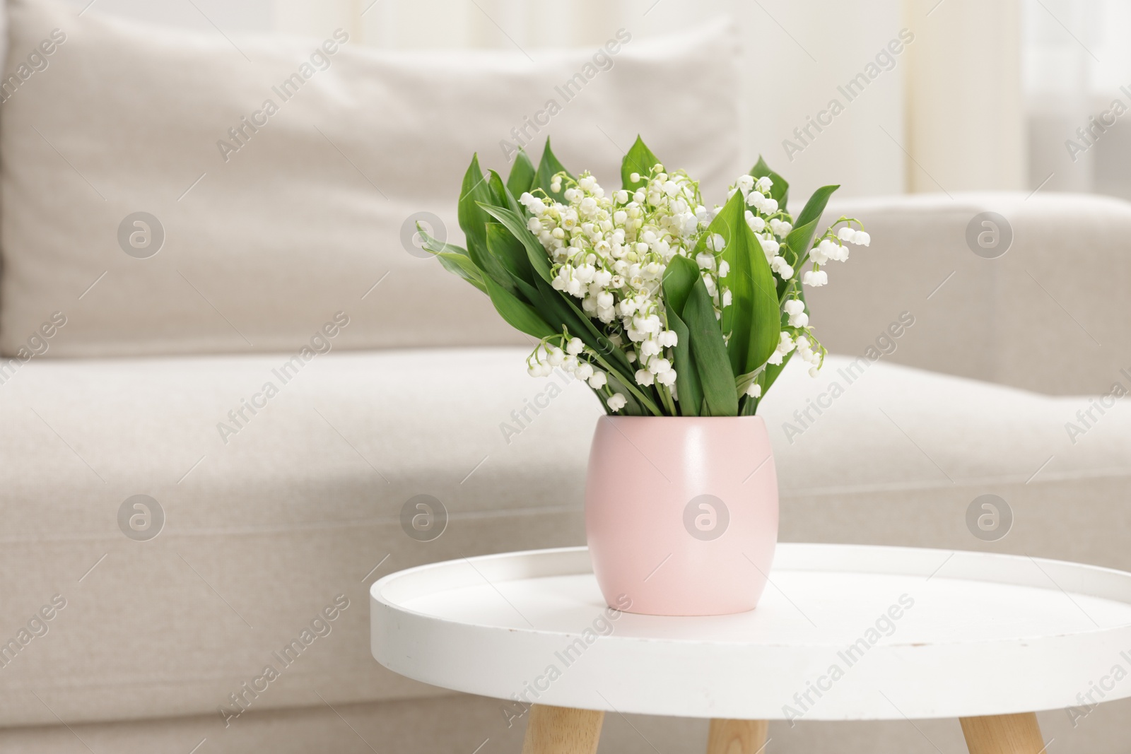 Bouquet of beautiful lily-of-the-valley on coffee table indoors. Space for text Photo of Bouquet of beautiful lily-of-the-valley on coffee table indoors. Space for text