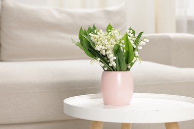 Photo of Bouquet of beautiful lily-of-the-valley on coffee table indoors. Space for text