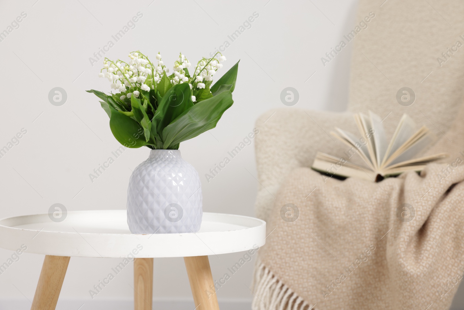 Bouquet of beautiful lily-of-the-valley in vase on coffee table indoors Photo of Bouquet of beautiful lily-of-the-valley in vase on coffee table indoors