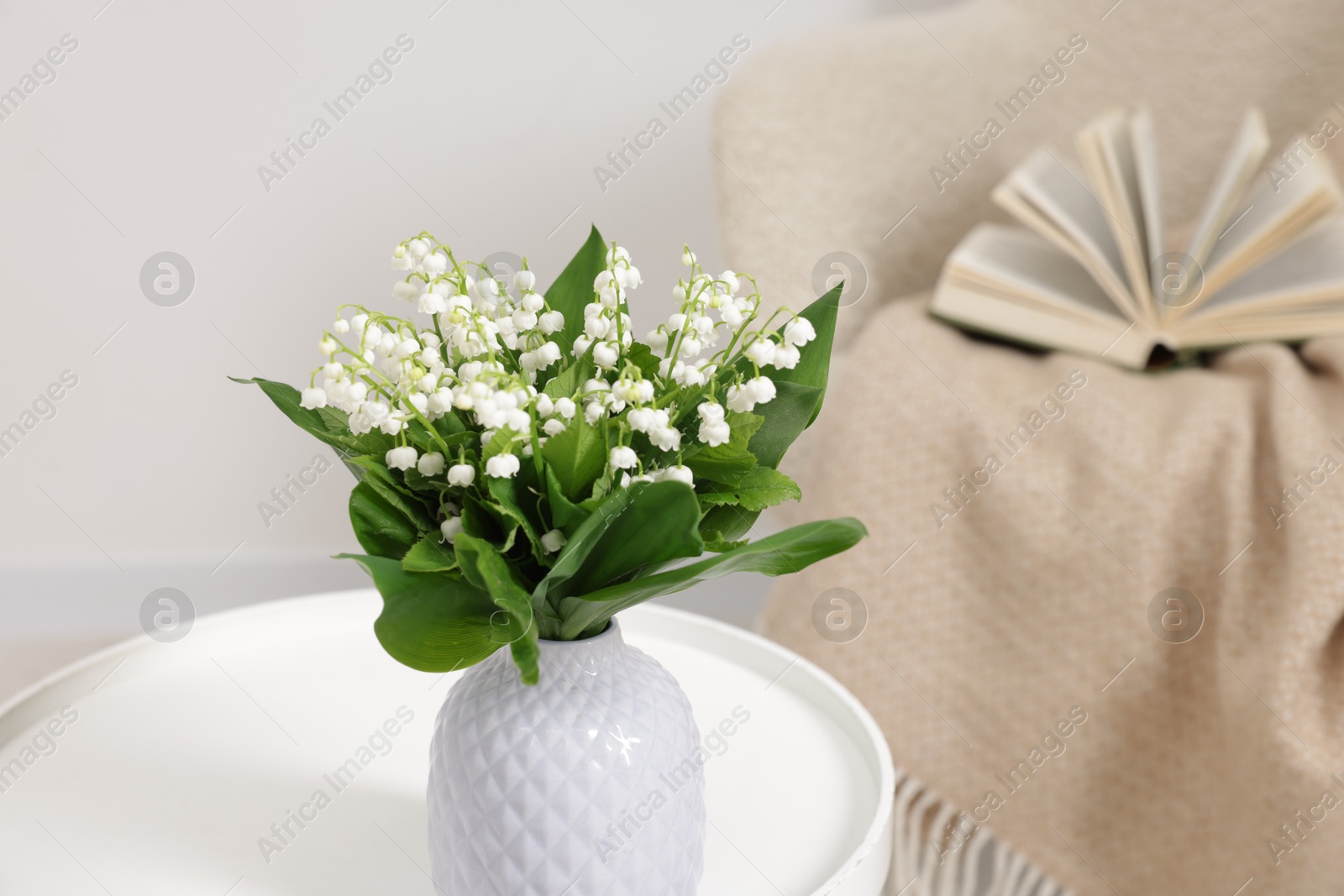 Bouquet of beautiful lily-of-the-valley in vase on coffee table indoors Photo of Bouquet of beautiful lily-of-the-valley in vase on coffee table indoors