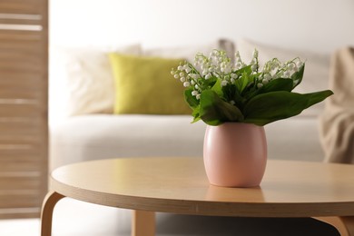 Photo of Bouquet of beautiful lily-of-the-valley on coffee table indoors