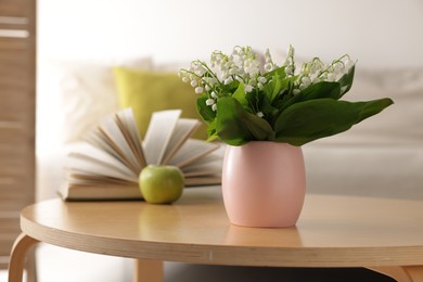 Photo of Bouquet of beautiful lily-of-the-valley on coffee table indoors