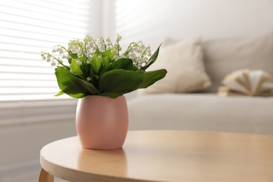 Photo of Bouquet of beautiful lily-of-the-valley on coffee table indoors