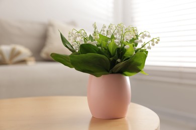 Photo of Bouquet of beautiful lily-of-the-valley on coffee table indoors, closeup